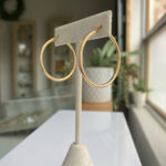Gold hoop earrings on a white display stand in a jewelry store showroom