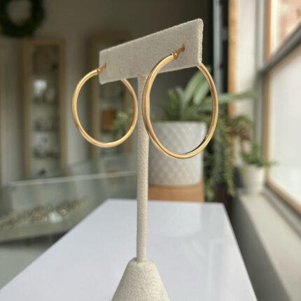 Gold hoop earrings on a white display stand in a jewelry store showroom