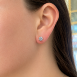 Close-up of a woman's left ear wearing a round-cut diamond stud earring on the earlobe.