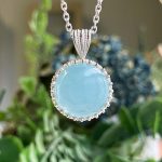 Close-up of a turquoise teardrop pendant with a silver beaded bezel hanging from a chain