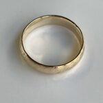 Gold wedding band with a smooth interior, photographed on a white surface