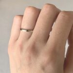 Close-up of a hand with a simple silver wedding band on the ring finger of the left hand.