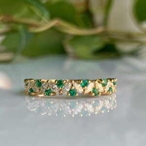 Gold band with alternating clear marquise-cut and green round gemstones set along the ring's circumference.
