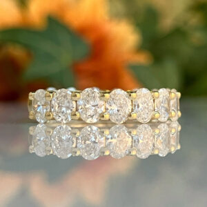Gold eternity ring with a continuous row of round diamonds on a reflective surface