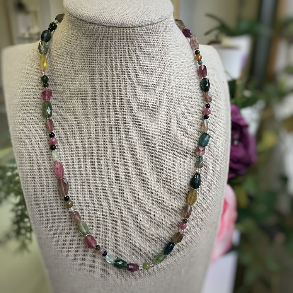 touramline necklacejpeg | Posy Fine Jewellery Toronto Beaded necklace with irregular multicolored gemstones draped around a beige display bust.