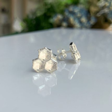 Silver hexagon cluster stud earring arranged on a glossy white surface, forming a honeycomb shape.