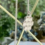 Silver honeycomb pendant on a delicate chain, with hexagonal panels forming a clustered shape.