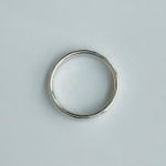 Silver circular band ring on a light gray background.