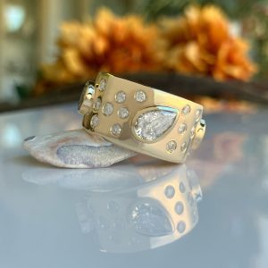 Close-up of a gold bracelet with numerous diamonds resting on a stone with a blurred warm background.