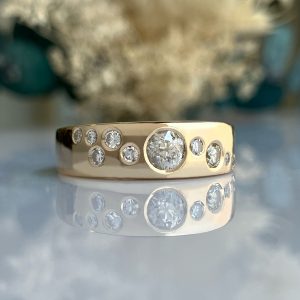 Close-up of a gold ring or bracelet with multiple round diamonds set in a row, on a reflective surface.