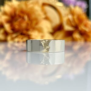 Close-up of a metal lighter with torn foil wrapped around the top, blurred autumn foliage in the background.