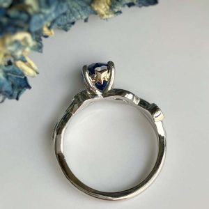 Silver ring with a blue gemstone and a small gold star accent at the setting, photographed from above on a light background.