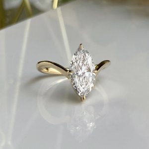 Gold ring with a marquise-cut diamond solitaire held by two prongs on a smooth gold band.