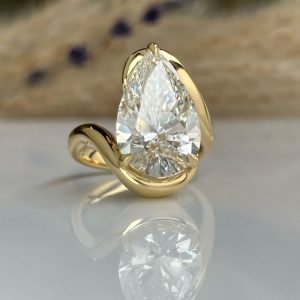 Gold ring with a large pear-shaped diamond centerpiece, gold band wrapping around the stone.
