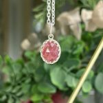 Oval pink gemstone pendant in a silver scalloped bezel on a silver chain.